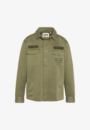 Oliwkowa koszula z guzikami, kurtka z dwoma kieszeniami na piersi, naszywkami "US 740 N" i "SCHOTT NYC" oraz nadrukowanym tekstem na prawej kieszeni.