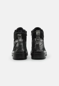 Svarte ankelstøvler med glitrende tekstur, semsket aksenter og en solid gummisåle. Designet inkluderer glidelåser på siden.