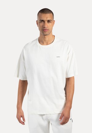 Weißes Baumwoll-T-Shirt mit rundem Halsausschnitt und kurzen Ärmeln. Verfügt über ein kleines Logo-Label auf der Brust, einen lockeren Schnitt und eine glatte Textur.