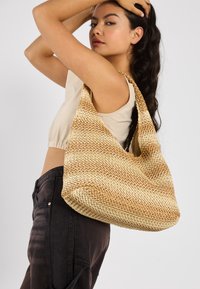 Veverket hobo-veske i naturlige beige nyanser, med en slapp form og en bred skulderrem for enkel bæring. Strukturert finish.