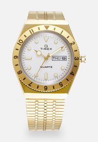 Orologio al quarzo dorato con quadrante bianco, cassa ottagonale, bracciale in maglia, indicatori delle ore neri, display della data e logo Timex.