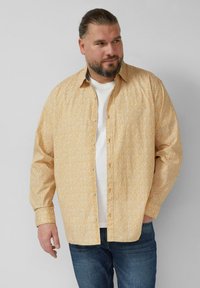 Koszula na guziki w jasnym żółtym kolorze z drobnymi, bia�łymi kwiatowymi wzorami. Posiada długie rękawy, luźny krój i klasyczny kołnierzyk.