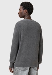 Szary sweter z dzianiny z długimi rękawami, okrągłym dekoltem i prążkowaną fakturą. Posiada luźny krój i prosty dół.
