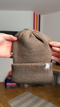 Pruun soonikuldsest koest müts soonilise tekstuuriga, mansetiga ja esiküljel logomärgiga. Kerge kangas, pehme väljanägemisega.