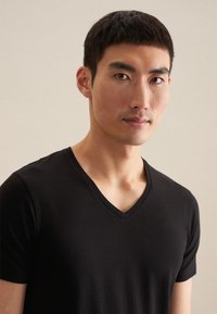 Sort V-hals t-shirt lavet af blødt stof, tætsiddende design, korte ærmer, glat tekstur, med en ren halsudskæring og minimal dekoration.