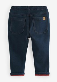 Pantalons en denim foncé avec une ceinture extensible, deux poches arrière et des accents rouges aux poignets roulés. Détails soigneusement cousus tout au long.