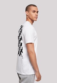 White cotton T-shirt featuring a black checkerboard pattern running vertically down the left side and a star accent.