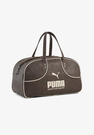 Bolsa de viaje marrón con ribetes blancos, dos asas, cremallera y gran logotipo blanco de Puma y texto “MACHT’S MIT QUALITÄT” en la parte delantera.