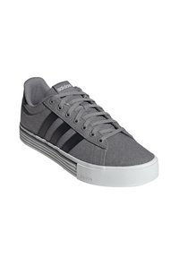 Gray canvas sneaker with three black stripes, rubber white sole, and gray laces. Features an Adidas logo on the tongue and side.