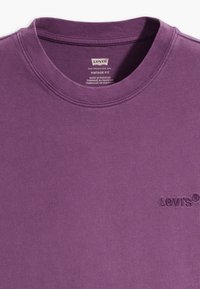 Fialové vintage tričko s kulatým výstřihem značky Levi's, s vyšívaným logem na hrudi a tištěným štítkem uvnitř límce.