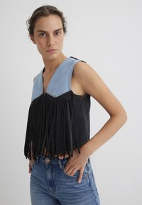 Schwarzes bauchfreies Top mit einem Jeanskragen, mit Fransen am unteren Saum und metallischen Nieten entlang des Halsausschnitts. Enganliegendes Design.