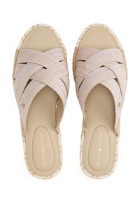 Beige slip-on szandálok párja, szövet pántokkal és kötél szegélyezésű talppal, a Tommy Hilfiger logójával a talpban és a pántokon.