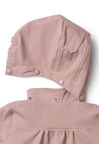 Ljusrosa regnjacka med en böjd huva, tryckknappar och en subtil volangnär. Tillverkad av ett slätt, vattentätt material.