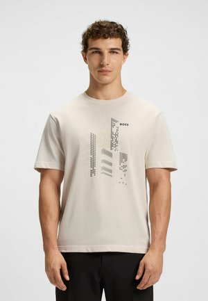 Beige T-Shirt mit kurzen Ärmeln aus weichem Stoff, featuring abstraktem Grafikdesign und schwarzem "BOSS"-Logo auf der Vorderseite. Glatte Textur.