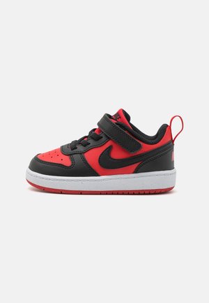Børnesneaker i lav model i rød og sort med hvid sål, med velcro-rem og Nike swoosh-logo på siden.
