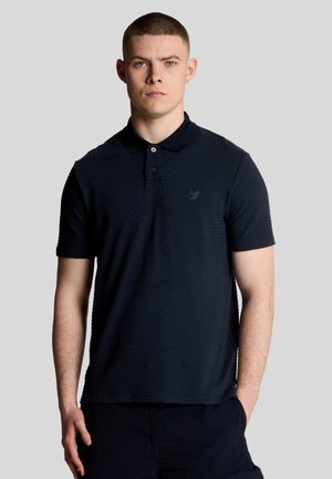 Polo shirt blu scuro con un motivo a nido d'ape testurizzato, maniche corte e colletto classico; presenta un logo ricamato discreto sul petto.