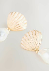 Orecchini a forma di conchiglia in tono oro, caratterizzati da una superficie texturizzata, con una perla bianca pendente sotto ciascuna conchiglia.