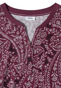 Col de chemise grenat avec motifs floraux et cachemire blancs complexes, découpe d'encolure fendue, et une étiquette de marque "CECIL" à l'intérieur du col.