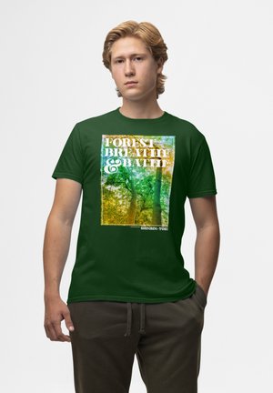 Grøn kortærmet t-shirt med et trykt skovmotiv og teksten "FOREST BREATHE & BATH" samt "SHINRIN-YOKU" nederst.