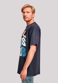 Navy blue t-shirt featuring colorful text, short sleeves, and a relaxed fit. Made from soft cotton with a smooth texture.