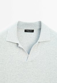 Szara koszulka polo z teksturowanym splotem, wyposażona w klasyczny kołnierz i małe wycięcie w kształcie litery V przy dekolcie. Zawiera metkę marki przy kołnierzu.