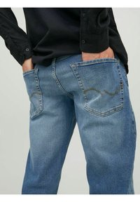 Ljusblå denimjeans med en avslappnad passform, som har två bakfickor med böjda sömmar och en mjuk, strukturerad ytfinish.