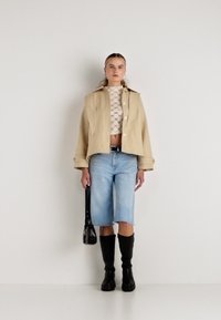 Bež jakna do struka, bela čipkasta majica, svetlo modre denim kratke hlače, črne boots do kolen in mala črna torbica. Preprost dizajn, različne teksture.