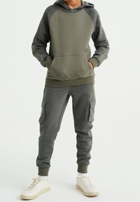 Mörkgrön huvtröja med raglanärmar och känguruficka, tillsammans med matchande cargo-sweatpants med sidfickor.