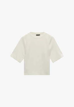 T-shirt à manches courtes, de couleur crème, en tissu doux. Il présente un col rond et une coupe décontractée. Aucun motif ni accent visible.