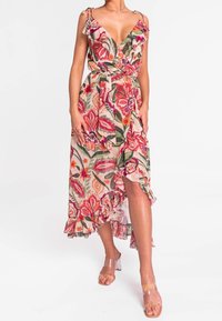 Blomsterindpakningskjole med flæsedetaljer, der har levende pink, rød og grønne mønstre på en lys baggrund. Halterneck-stropper og asymmetrisk kant.
