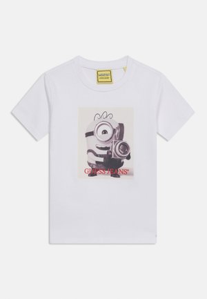 Biała koszulka z Minionem trzymającym aparat retro z napisem "GUESS JEANS" na czerwono pod postacią.