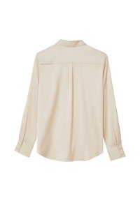 Blusa lunga beige chiaro a maniche lunghe con colletto, spalle a yoke e polsini con bottone. Tessuto liscio con vestibilità rilassata e un leggero lucido.