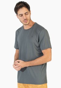 Camiseta gris de manga corta con cuello redondo y tejido texturizado, que presenta un pequeño y sutil logotipo en el pecho.