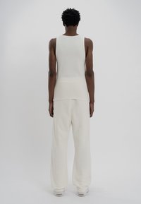 White ribbed tank top and loose wide-leg pants, made of soft fabric, with a relaxed fit. The outfit has a smooth texture and minimal design.