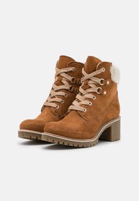Hnědé semišové kotníkové boty s texturovaným šněrováním, kovovými očky, umělým kožešinovým límcem a robustním blokovým podpatkem. Pevná gumová podrážka.