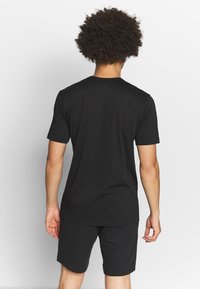 Black short-sleeve t-shirt with a round neckline, made of soft fabric. Paired with matching black shorts, minimalistic design.