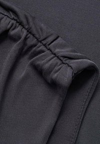 Dunkelgrauer Stoff mit einer weichen, strukturierten Oberfläche. Verfügt über eine geraffte Naht am Rand, die ein glattes, dehnbares Design zeigt.