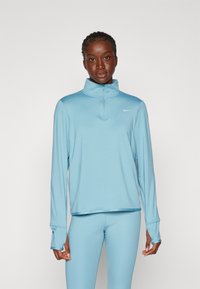 Lichtblauw sporttop met een hoge kraag en ritssluiting, gemaakt van zachte stof. Lange mouwen hebben duimgaten. Gecombineerd met bijpassende leggings.