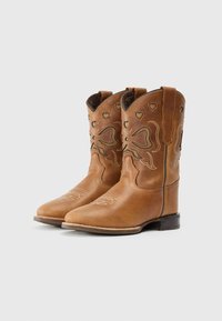 Stivali da cowboy in pelle marrone con cuciture decorative, ritagli a forma di cuore e punte arrotondate. Presentano un tacco impilato e linguette per indossarli.