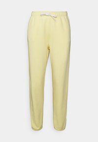 Gula sweatpants med dragsko i midjan, avsmalnande ben och mjukt bomullstyg. Inga fickor eller synliga detaljer i metall.