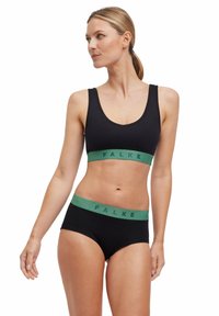Zwart naadloos lingeriesetje met een cropped bralette met een groene FALKE-band en bijpassende hoge briefs, met een focus op de soepele stof en constructie.