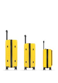 Three yellow hard-shell suitcases in varying sizes, each with a black zipper, smooth texture, and four wheels for mobility.