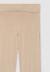Leggings beige realizzati in un tessuto liscio ed elasticizzato. Presentano una vita alta e un design elegante senza motivi o dettagli prominenti.