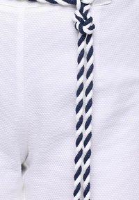 Tessuto bianco con un motivo testurizzato, con un dettaglio di cintura in corda attorcigliata blu e bianca legato in vita.