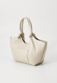 Beige skinnveske med knyttede håndtak, strukturert form og en frontlomme. Glatt tekstur og minimalistisk design.