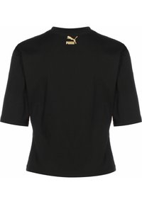 Melnas īsām piedurknēm T-krekls ar vienkāršu apaļu apkakli. Aizmugurē ir zelta Puma logo, izgatavots no mīksta kokvilnas materiāla.