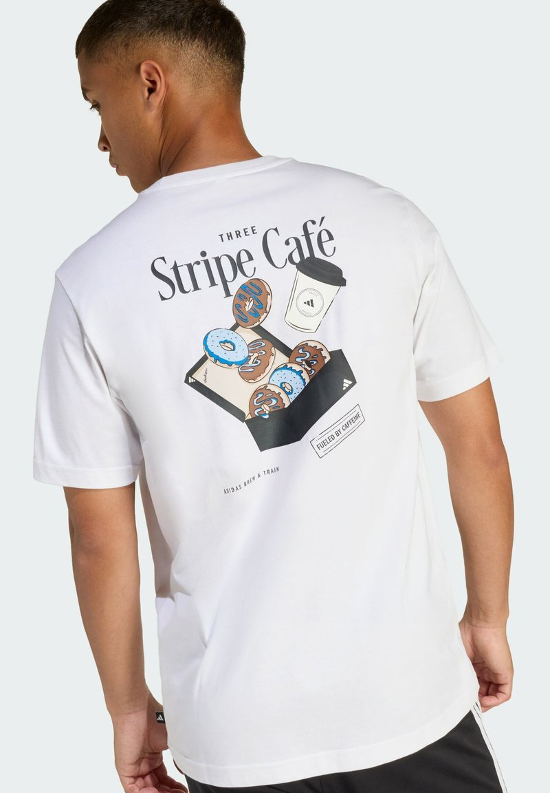 Biała bawełniana koszulka z kolorową grafiką przedstawiającą pączki i filiżankę kawy, z napisem "Three Stripe Café" z tyłu. Standardowy krój.