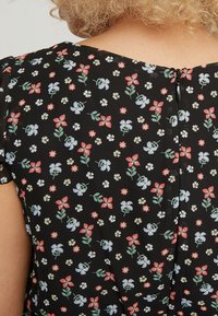 Czarna tkanina w kwiatowy wzór z czerwonymi, niebieskimi i białymi kwiatami. W zestawie ma mały zamek z tyłu i krótkie rękawy.