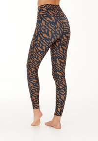 Hoch geschnittene Leggings mit einem marineblauen Grundton und einem braunen Tierdruckdesign. Der Stoff ist dehnbar und glatt, entworfen für Komfort und Flexibilität.
