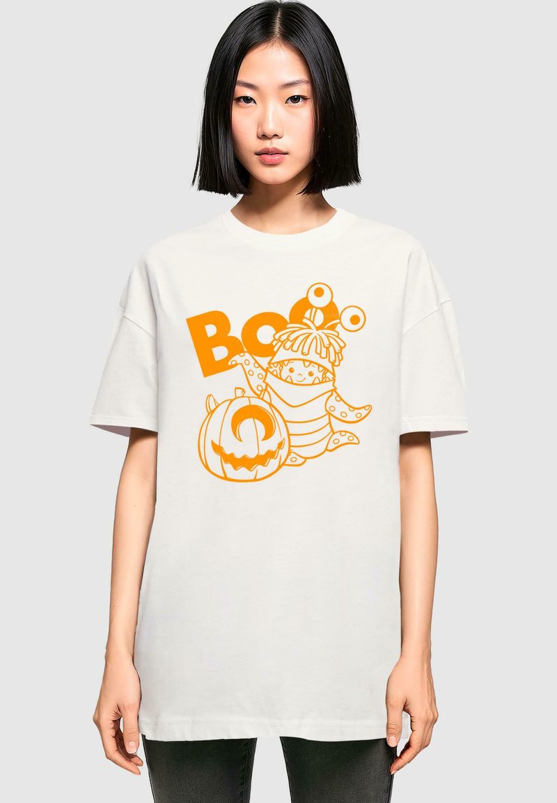 Hvid oversized t-shirt med et orange grafik af en tegneserie-frog, græskar og teksten "Boo." 100% bomuldsstof med en blød tekstur.
